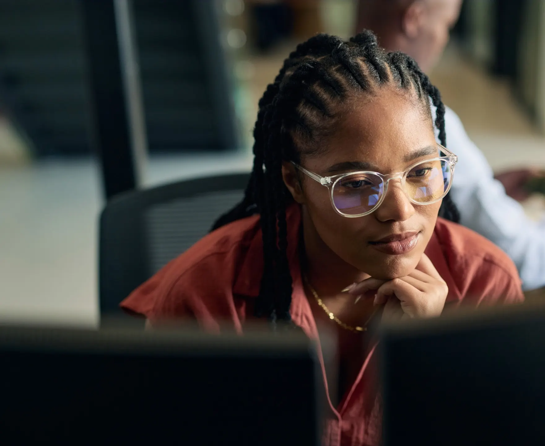 Young professional at a desk, chin on her hand, looking at her screen